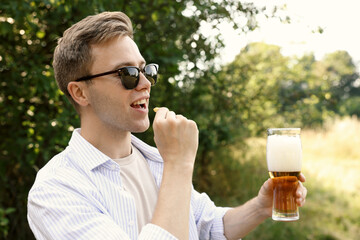 Fototapeta premium Handsome young man with glass of beer outdoors