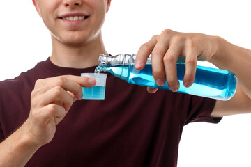 Man pouring mouthwash into cap on white background, closeup. Oral hygiene