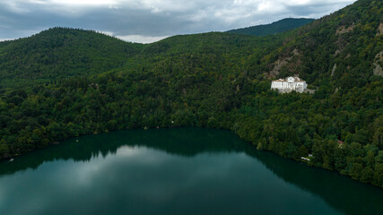 Fototapeta premium Aerial view of Lake Monticchio Piccolo, located in the crater of the ancient extinct volcano of Vulture Mount. It is located in the province of Potenza, Basilicata, Italy, and is surrounded by trees.
