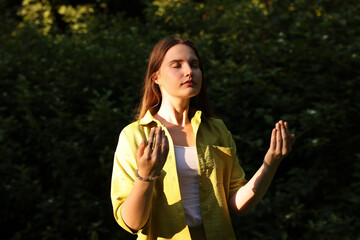 Woman meditating to heal or restore her aura in nature