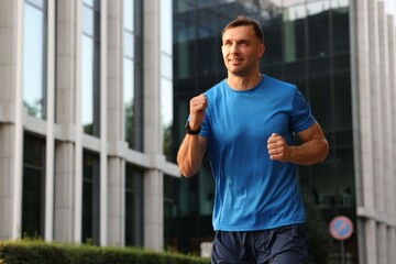 Man in sportswear running outdoors, low angle view. Space for text