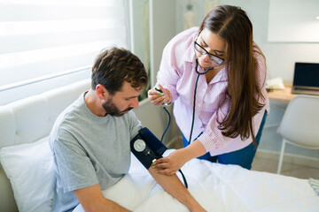 Obraz premium Doctor measuring blood pressure of recovering patient at home