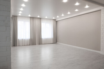 Empty room with beige wall, large window and wooden floor