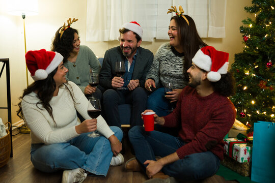 Cheerful group celebrating christmas party with wine laughing