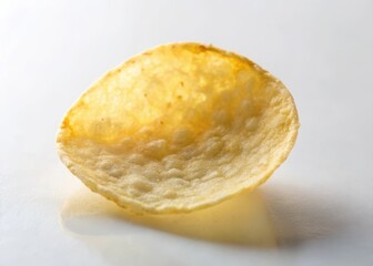 A single round potato chip partially exposed on a white surface