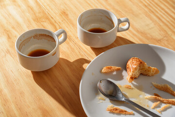 Empty espresso cups and croissant crumbs on white plate