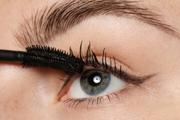 Woman applying mascara onto her eyelashes, closeup