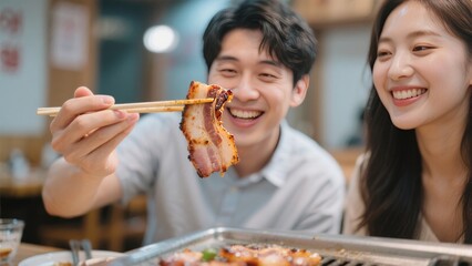 Delightful Dining: A young couple shares a happy moment, savoring delicious grilled meat with chopsticks, embodying a cheerful dining experience. 