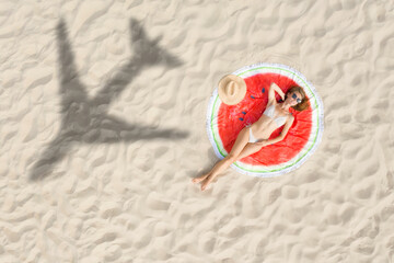 Woman sunbathing on beach, top view. Flying airplane casting shadow on sand