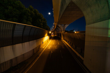 An empty street under the city overpass in Tokyo at night wide shot
