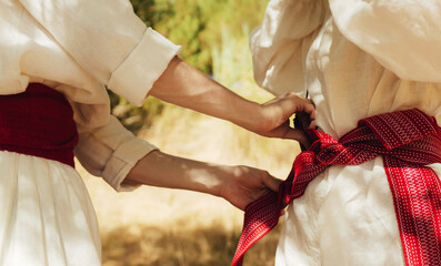 Close-up of Ukrainian traditional costume embroidered vyshyvanka blouse, woven belt kraika, folk jewelry. Ethnic festive clothing, national outfit details, cultural heritage. Part of the series