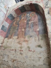 Weathered fresco of three haloed saints under arched vault