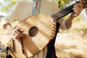 Close-up of man's hands with Ukrainian traditional musical string instrument - kobza. Folk ethnic music, cultural heritage, authentic national clothing. Part of the series