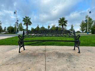 iron bench on the street near the green grass in blue sky in the city of Martil, Tetouan. morocco