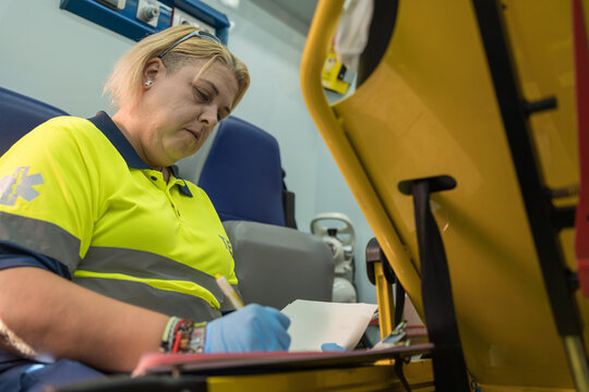 Female paramedic taking notes inside ambulance after emergency call - Powered by Adobe