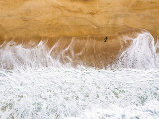 Aerial View of Surfer with Surfboard Walking Along Sandy Beach in Nazare, Portugal