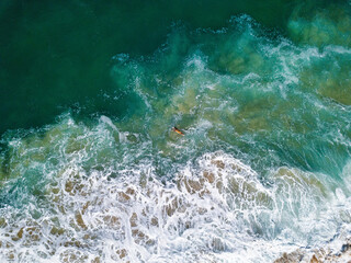 Aerial View of surfer floats on a board in Nazare, Portugal