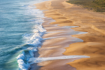 Golden Sandy Beach with Rolling Atlantic Ocean Waves in Nazare, Portugal, Famous Surf Destination
