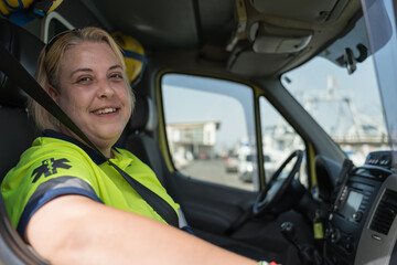 Smiling female paramedic wearing uniform sitting in ambulance