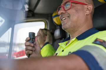 Smiling paramedic using walkie talkie in ambulance vehicle