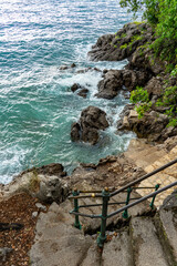 Rocky seaside with turquoise waves and stone steps leading to the ocean Lungomare Opatija Croatia