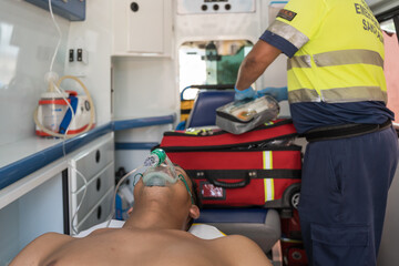 Paramedic assisting unconscious man wearing oxygen mask in ambulance