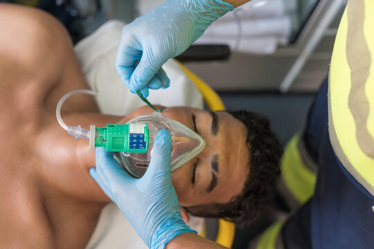 Paramedic adjusting oxygen mask on patient during emergency