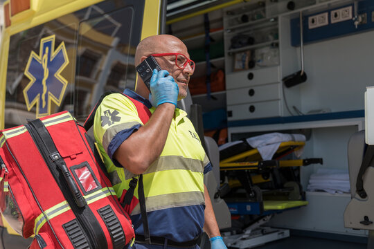 Paramedic wearing blue gloves talking on phone near ambulance