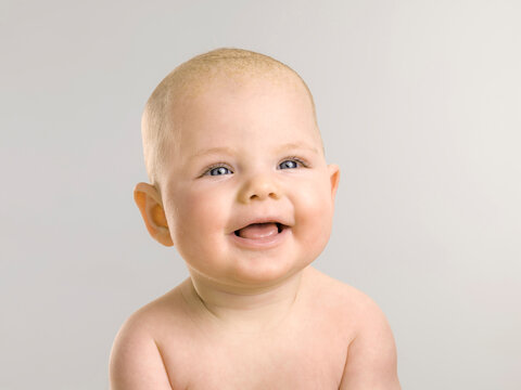 Portrait of young baby, six months old, laughing and looking into the camera.