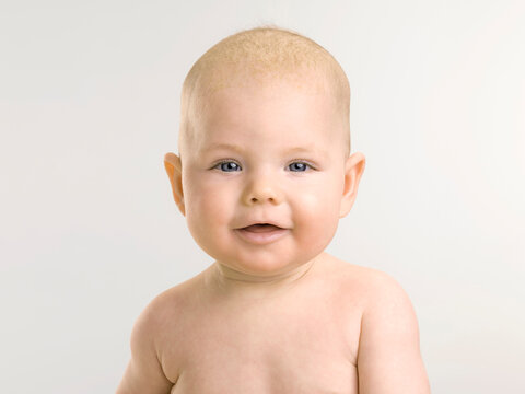 Portrait of young baby, six months old, laughing and looking into the camera.