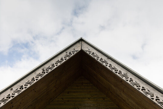 A close-up view of a wooden roof gable featuring intricate decorative trim