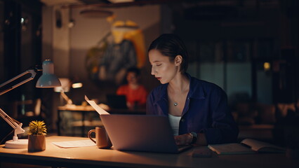Woman analyst unmotivated overtime work reading papers in night office closeup.