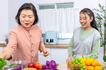 Mother and daughter family kitchen activity, senior parent with young adult daughter preparing fruit juice drink, Asian lifestyle showing health support, happiness and generation bonding wellness