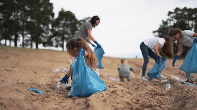 Volunteer and family collect trash on beach in community cleanup with child picking plastic bottle and bag using glove adults gather litter helping environment and protecting wildlife from pollution