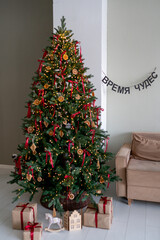 Christmas interior: a christmas tree next to a beige sofa in a bright room.