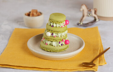 Macarons in the shape of a Christmas tree with sugar, cup of tea on a yellow napkin.