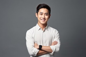 Studio portrait of a cheerful asian businessman smiling with crossed arms, conveying confidence and professionalism