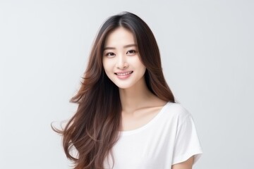 Naklejka premium Studio portrait of a beautiful young asian woman smiling, showcasing her healthy long brown hair against a clean white backdrop