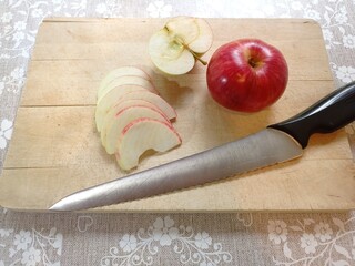 Some autumn treats. Top view of a red apple and apple slices on a wooden cutting board with a knife.