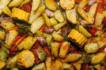 Colorful assortment of roasted vegetables including potatoes, corn, and garlic, seasoned with herbs, creating a vibrant and appetizing dish ideal for healthy meals