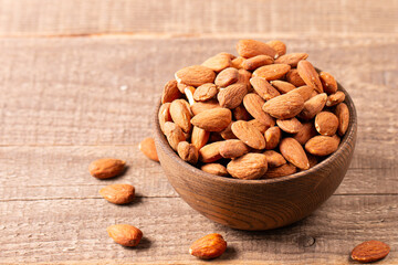 Raw peeled almonds in brown wooden bowl. Organic food concept. 