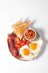 Delicious traditional English breakfast with fried eggs, beans, bacon, tomatoes and toasts