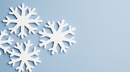 A collection of white snowflakes arranged in a loose cluster against a light blue background.