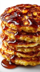 A close up shot of a stack of golden brown pancakes drenched in a dark, rich syrup. The pancakes are fluffy and appear delicious.