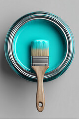 A top view of a can of turquoise paint and a brush partially dipped in the paint