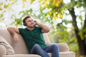 Happy man listening to sounds of nature which making him feel calm. Beautiful landscape on background