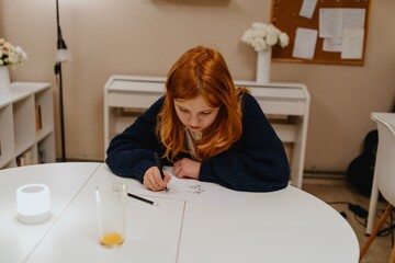 A teenage girl studies in the living room during evening hours, drinking coffee while focusing on...