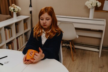 A teenage girl studies in the living room during evening hours, drinking coffee while focusing on...