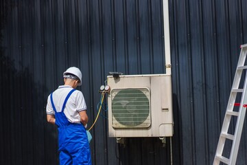 Technician Conducting Maintenance on Air Conditioning Unit with Ladder Nearby for Efficient Cooling Solutions