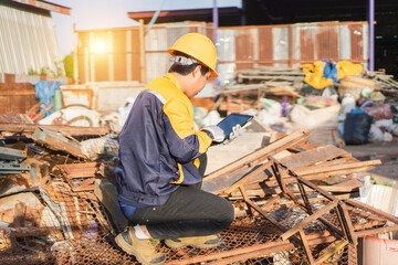 Construction Worker Using Tablet for Inventory Management in Scrap Yard with Sunshine Background